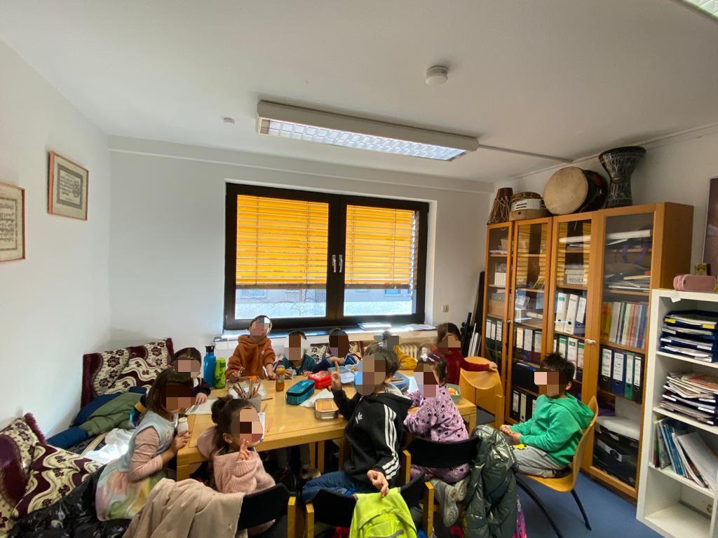 Kinder sitzen gemeinsam an einem Tisch in einem Raum des Iman Zentrums